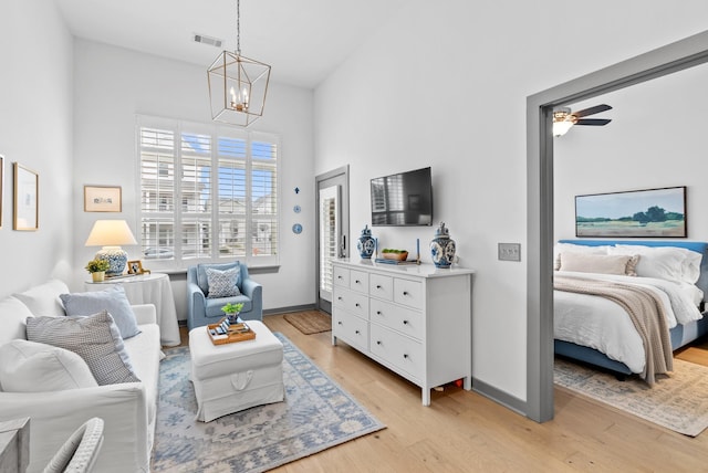 living area with ceiling fan with notable chandelier and light wood-type flooring