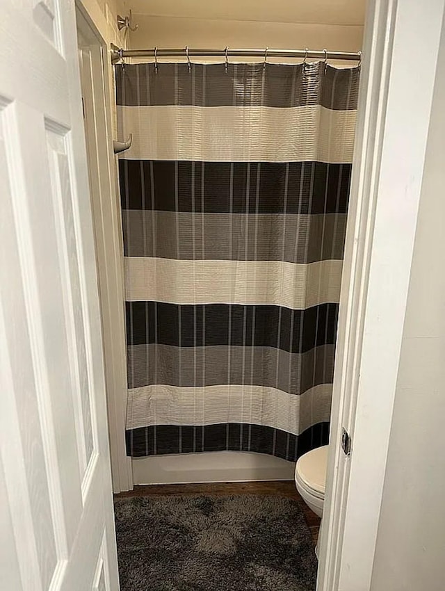 bathroom featuring toilet and curtained shower