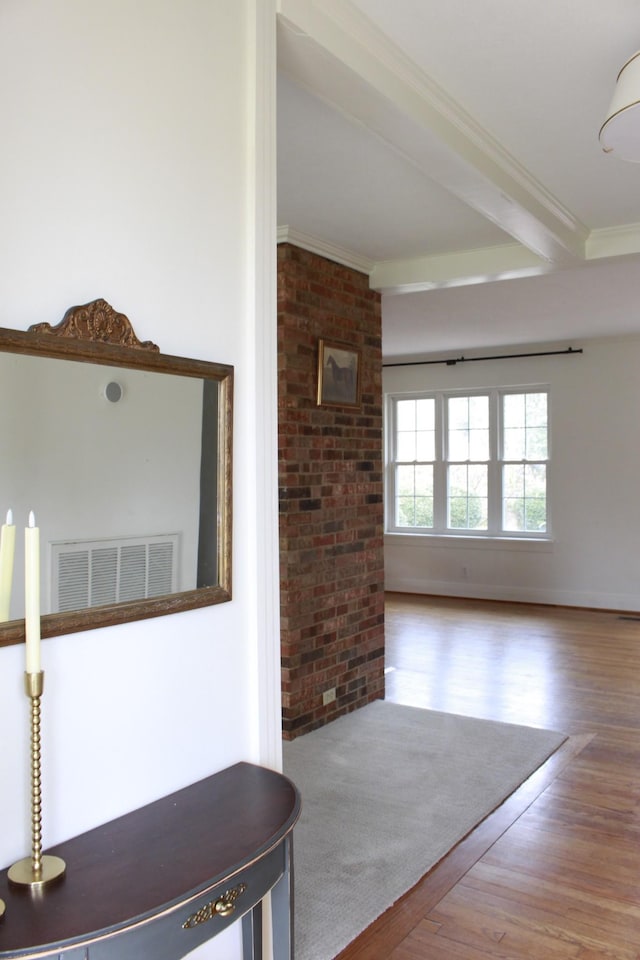 corridor with hardwood / wood-style flooring, crown molding, brick wall, and beamed ceiling