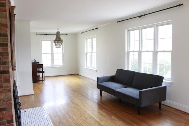 living area with a brick fireplace, light hardwood / wood-style flooring, and a chandelier