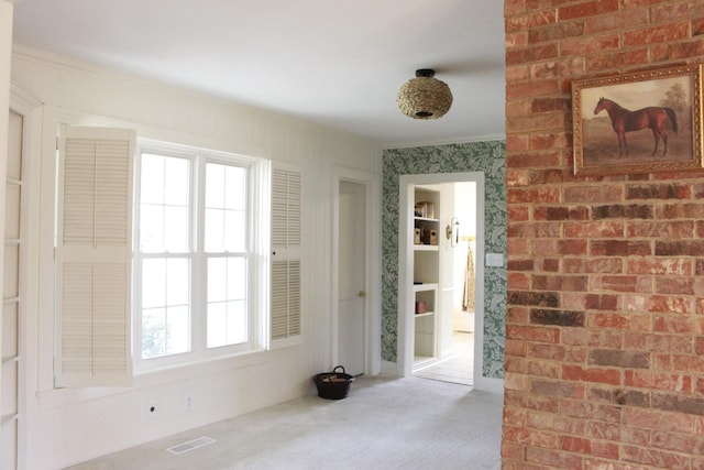 empty room featuring carpet floors, ornamental molding, and brick wall