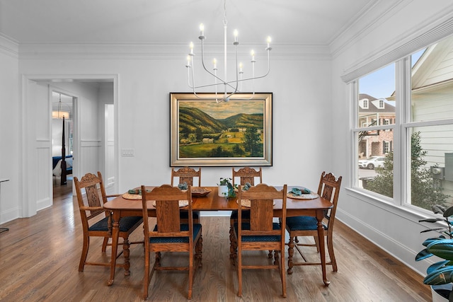 dining area with hardwood / wood-style floors, crown molding, and a chandelier