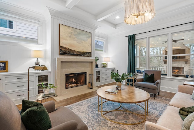 living room with beamed ceiling, wood-type flooring, coffered ceiling, a premium fireplace, and an inviting chandelier