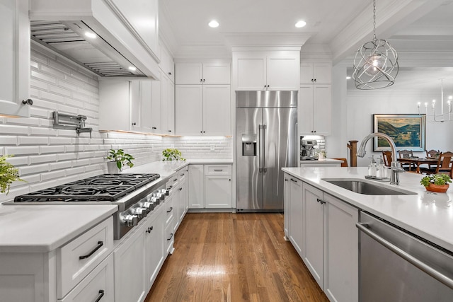 kitchen with pendant lighting, sink, premium range hood, white cabinetry, and stainless steel appliances