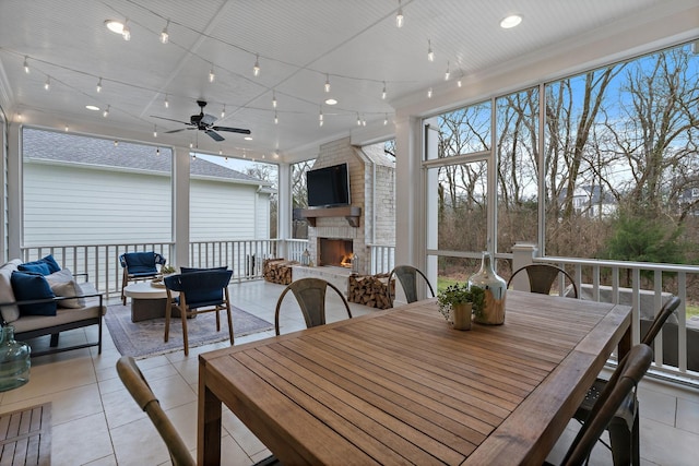 dining room with light tile patterned floors, rail lighting, a large fireplace, and ceiling fan