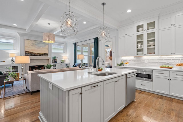 kitchen with sink, white cabinetry, a center island with sink, pendant lighting, and beam ceiling