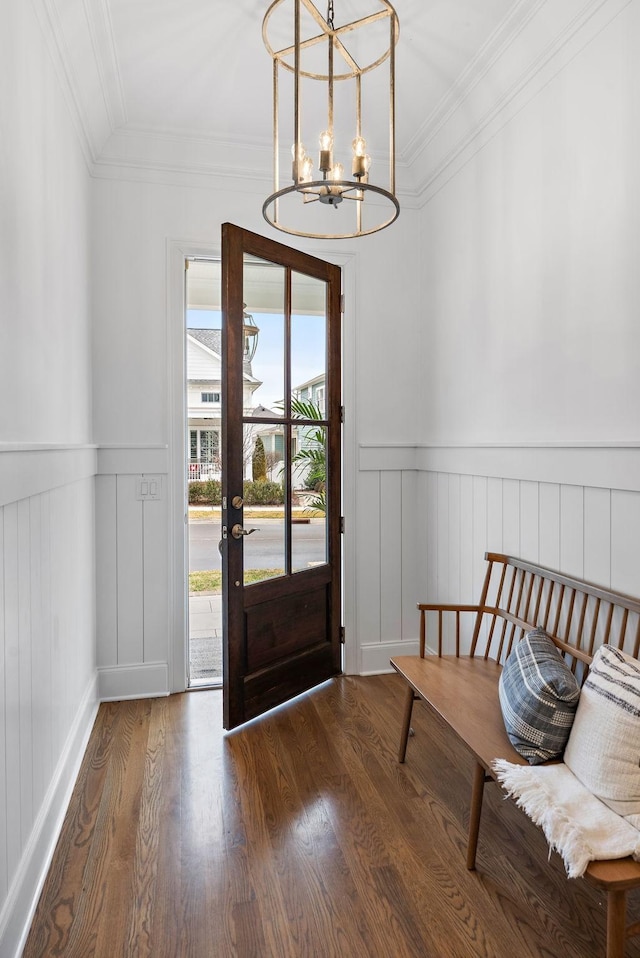 foyer entrance with dark wood-type flooring, crown molding, and a notable chandelier