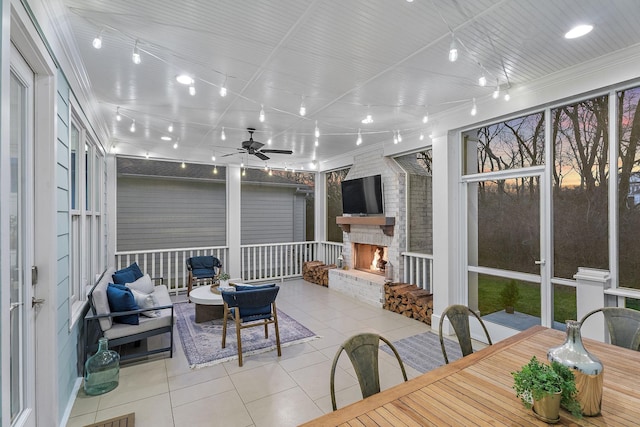 sunroom / solarium featuring a stone fireplace, rail lighting, and ceiling fan