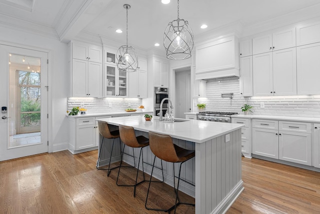 kitchen with white cabinetry, sink, a kitchen breakfast bar, a kitchen island with sink, and light hardwood / wood-style floors