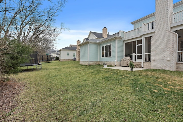 view of yard with a trampoline, a patio, and a balcony