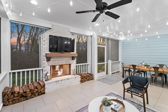 sunroom with rail lighting, a large fireplace, and ceiling fan