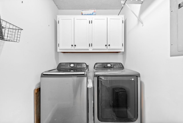 washroom featuring a textured ceiling, washing machine and dryer, cabinets, and electric panel