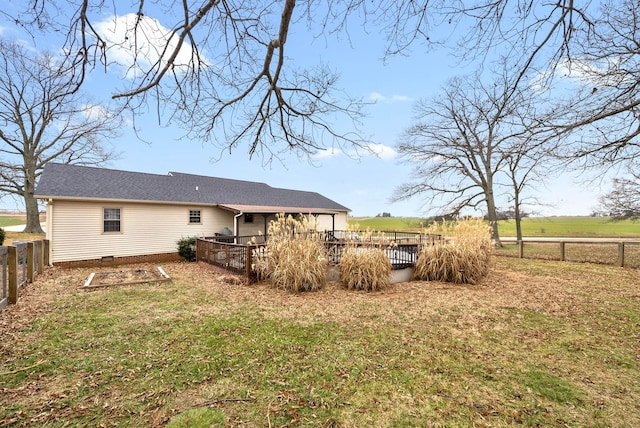 back of house with a rural view, a deck, and a lawn