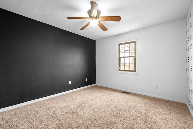 empty room with ceiling fan, carpet, and a textured ceiling