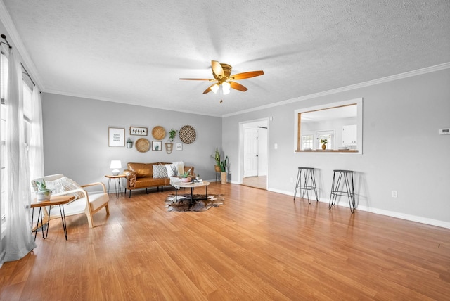 living room featuring ceiling fan, crown molding, light hardwood / wood-style floors, and a textured ceiling