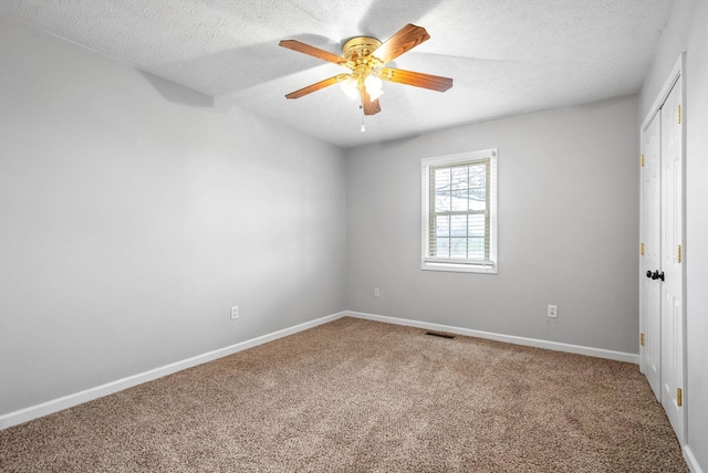 unfurnished room with ceiling fan, carpet floors, and a textured ceiling