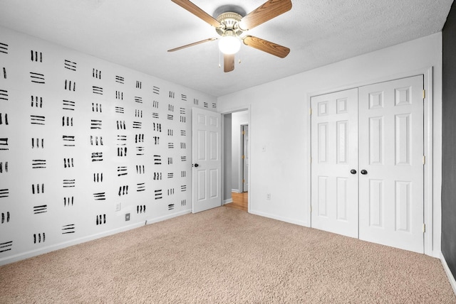 unfurnished bedroom with ceiling fan, a closet, carpet flooring, and a textured ceiling