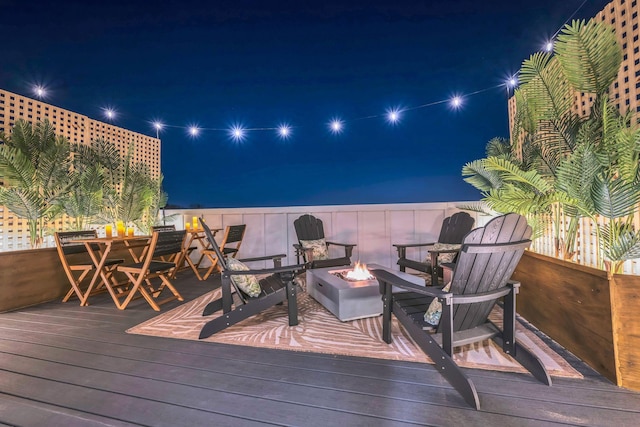 deck at twilight featuring a fire pit and a water view