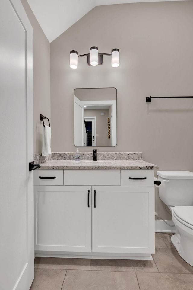 bathroom featuring vanity, lofted ceiling, tile patterned floors, and toilet