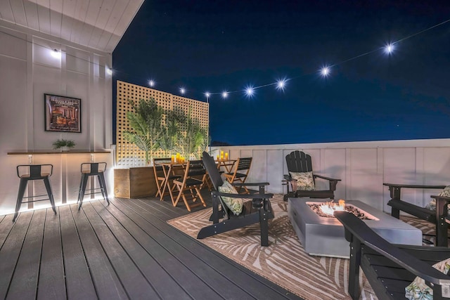 deck at twilight with exterior bar and an outdoor fire pit