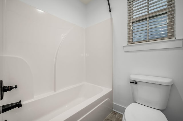 bathroom with tile patterned floors, washtub / shower combination, and toilet