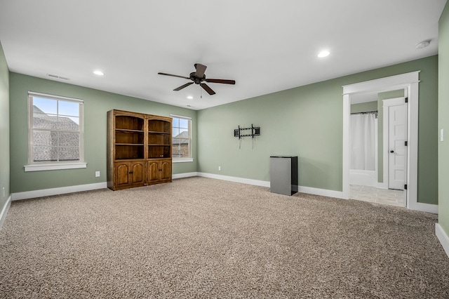 interior space featuring ceiling fan, carpet floors, and multiple windows