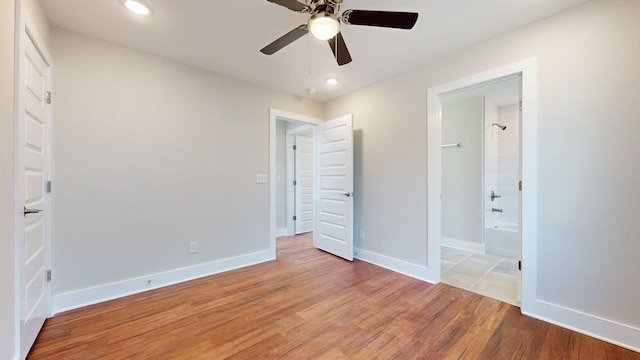 unfurnished bedroom featuring connected bathroom, wood-type flooring, and ceiling fan