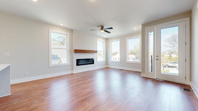 unfurnished living room with heating unit, ceiling fan, and light hardwood / wood-style flooring