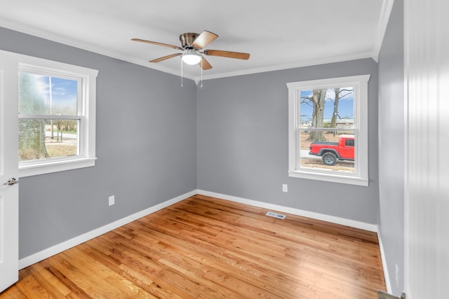 spare room with plenty of natural light, ornamental molding, and light wood-type flooring