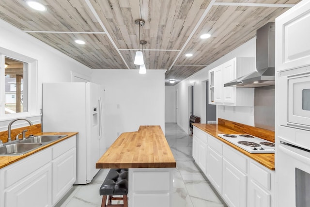 kitchen featuring wood counters, wall chimney range hood, white appliances, and sink