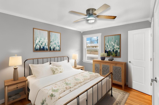 bedroom with ornamental molding, ceiling fan, and light hardwood / wood-style floors