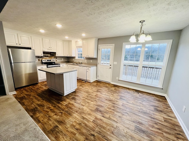 kitchen featuring sink, a kitchen island, pendant lighting, stainless steel appliances, and white cabinets