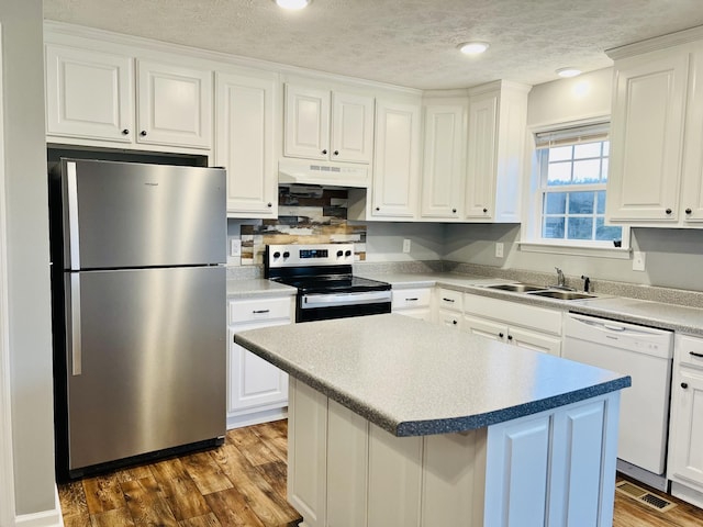 kitchen with stainless steel appliances, sink, a kitchen island, and white cabinets