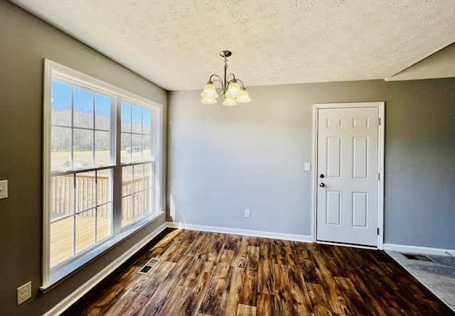 unfurnished dining area featuring an inviting chandelier, dark hardwood / wood-style floors, and a textured ceiling