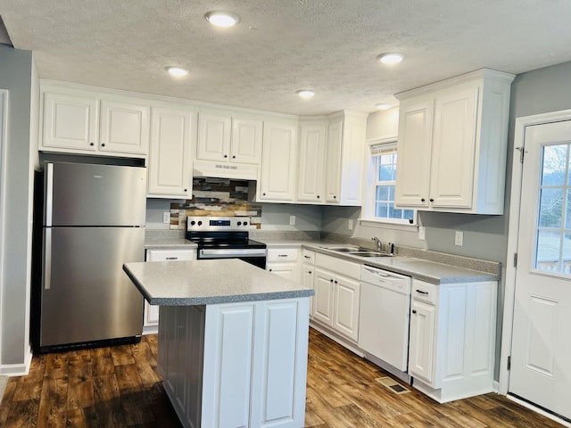 kitchen with stainless steel appliances, a kitchen island, white cabinets, and dark hardwood / wood-style flooring