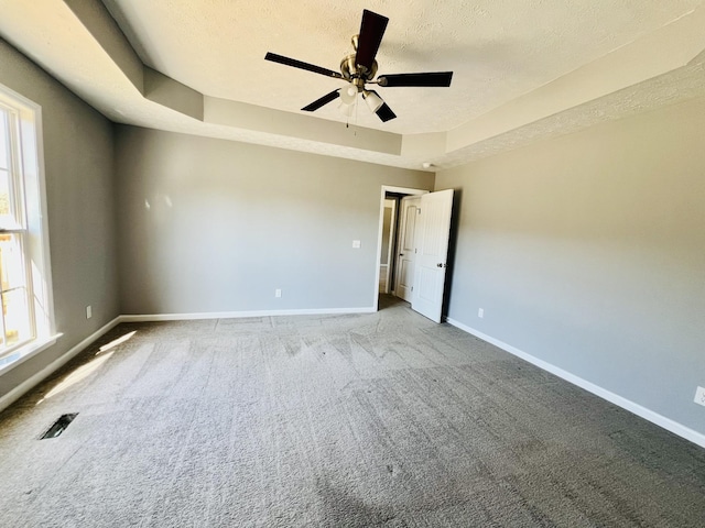 carpeted empty room with a raised ceiling, ceiling fan, and a textured ceiling