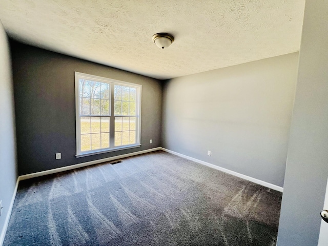 carpeted empty room featuring a textured ceiling