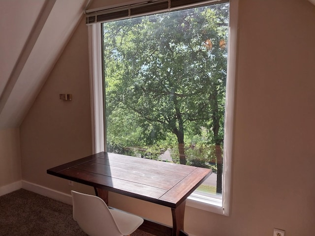 unfurnished dining area featuring dark colored carpet and lofted ceiling