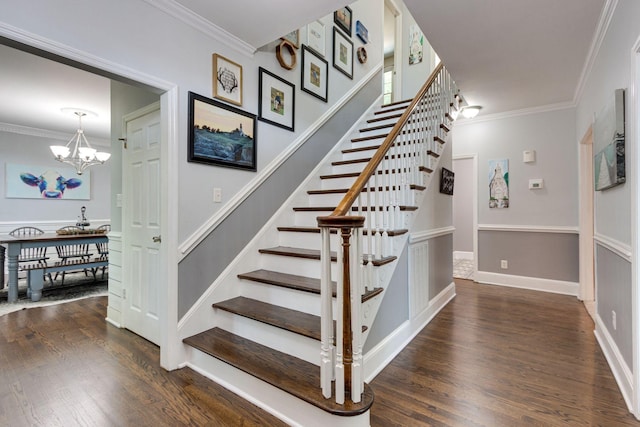 staircase featuring crown molding, wood-type flooring, and an inviting chandelier