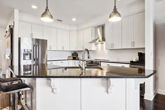 kitchen with sink, a breakfast bar, stainless steel appliances, white cabinets, and wall chimney exhaust hood