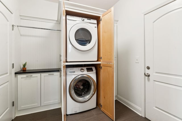 laundry room with dark wood-type flooring and stacked washer / dryer