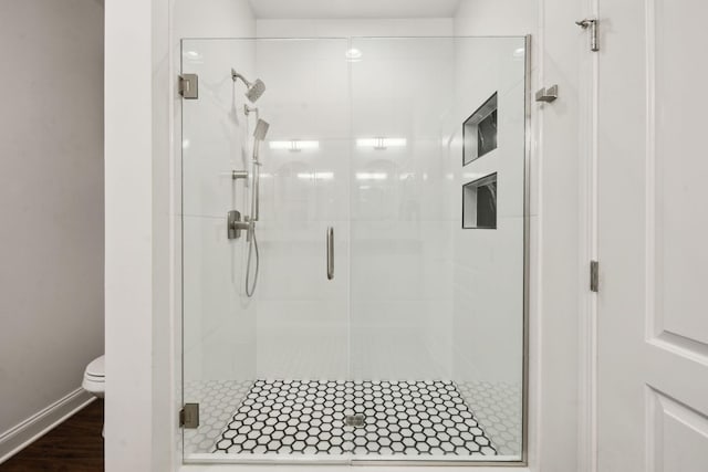 bathroom featuring an enclosed shower, hardwood / wood-style flooring, and toilet