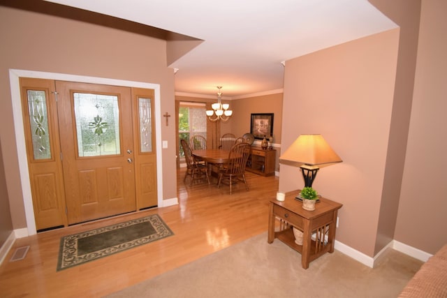 foyer entrance with crown molding, a chandelier, and hardwood / wood-style flooring