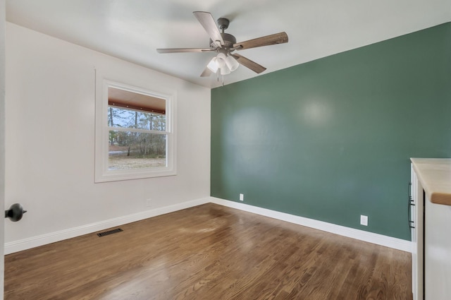 empty room featuring dark wood-type flooring and ceiling fan