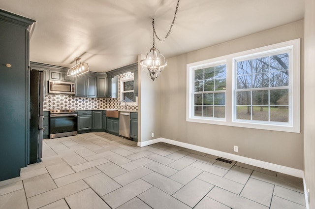 kitchen with gray cabinetry, hanging light fixtures, light tile patterned floors, stainless steel appliances, and decorative backsplash