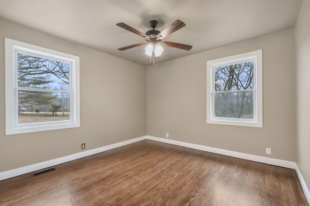 empty room featuring wood-type flooring, plenty of natural light, and ceiling fan