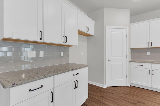 kitchen featuring light stone counters, tasteful backsplash, dark hardwood / wood-style floors, and white cabinets