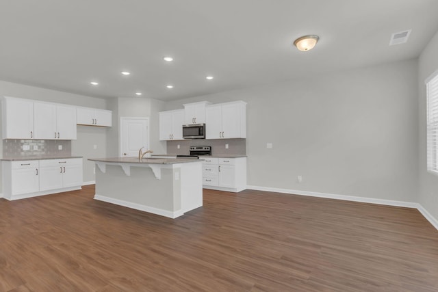 kitchen with white cabinetry, appliances with stainless steel finishes, dark hardwood / wood-style flooring, and a center island with sink