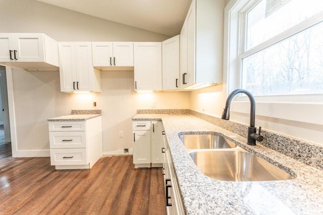 kitchen with light stone countertops, sink, and white cabinets