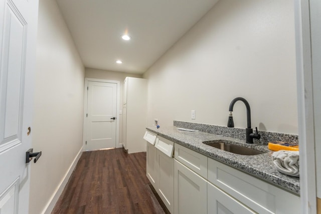 interior space featuring light stone counters, sink, white cabinetry, and dark hardwood / wood-style floors